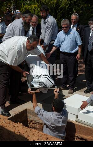 Orthodox Jewish pallbearers lower the shroud-covered body of renowned Holocaust survivor and Nazi-hunter Simon Wiesenthal into a grave at his funeral in the town of Herzliya in Israel. Holocaust survivor Wiesenthal dedicated his life to raising public awareness of the need to hunt and prosecute Nazis who had evaded justice. Stock Photo
