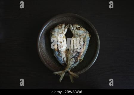 Fried two short bodied mackerel fishes on black background. Popular fish menu in Thailand. Stock Photo