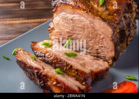 Homemade slow cooked oven-pulled pork shoulder on plate with green onion and tomato, close-up. Selective focus Stock Photo