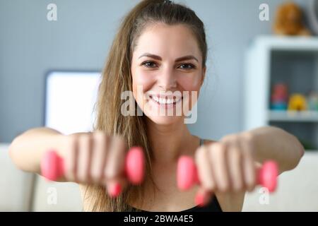 Happy girl doing exercises with dumbbells at home Stock Photo