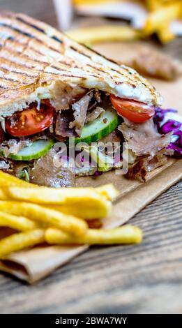 Doner kebab with vegetables and french fries on wood table Stock Photo