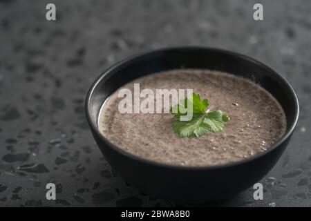 Mushroom soup puree in black bowl on concrete background Stock Photo