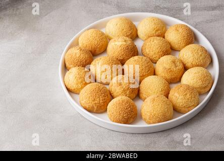 Chou pastry cookies in a white plate isolated on gray background. Concept: bakery, french dessert. Copy space Stock Photo
