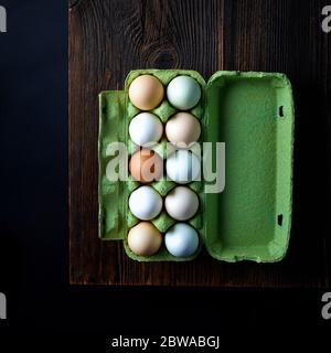 Fresh eggs from local farm in cardboard box on black background, top view Stock Photo