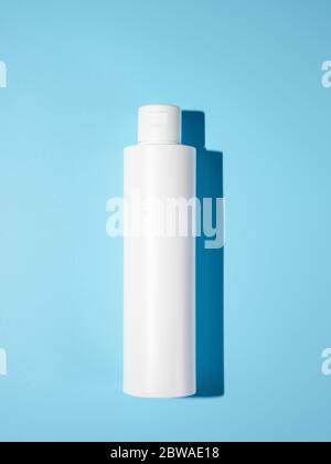 Empty white plastic bottle mockup in hard light. Top view or flat lay. Blank opaque bottle without packaging on blue background. Mock up for package design Stock Photo