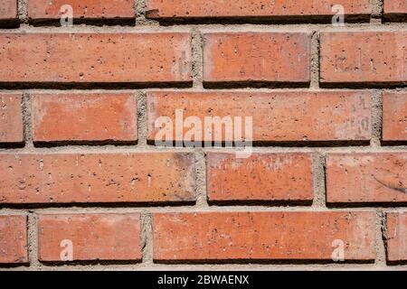 Wall of dirty orange bricks under sunlight. Close-up. Stock Photo