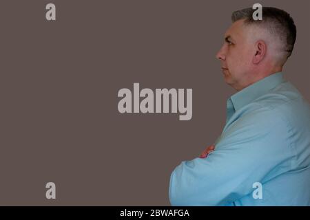 Middle aged man portrait with crossed hand. Profile side view on isolated background. 40 years man not looking at camera. Blue business shirt is dress Stock Photo