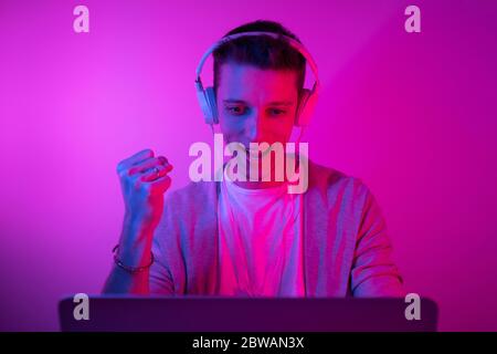 Gamer plays on a laptop. The programmer writes the code. Man on a colored background Stock Photo