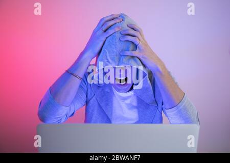 Gamer plays on a laptop. The programmer writes the code. Man on a colored background Stock Photo