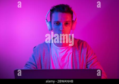 Gamer plays on a laptop. The programmer writes the code. Man on a colored background Stock Photo