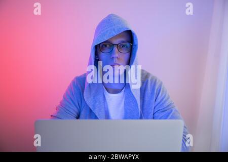 Gamer plays on a laptop. The programmer writes the code. Man on a colored background Stock Photo