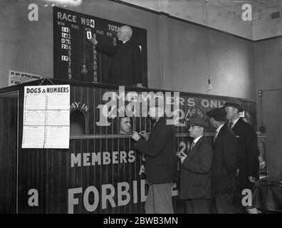 Father Carless of St Ann ' s Custom House Roman Catholic Church , paying out and putting up the winning numbers at the tote club he has founded . By running this he hopes to repay the cost of his £ 11 , 000 building works 11th October 1932 Stock Photo