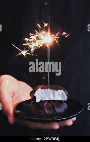 Chocolate marshmallows with sparklers, design food, dark mood on black background Stock Photo