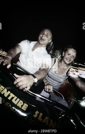 A young adult couple enjoying a roller coaster ride at night at Adventure Island. Southend-on-Sea. Essex. England, UK Stock Photo