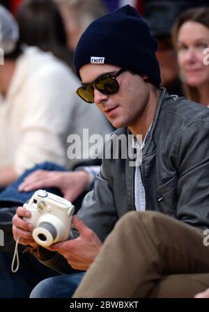 Zac Efron wearing beanie, holding camera at LA Lakers NBA game, December 2014 Stock Photo