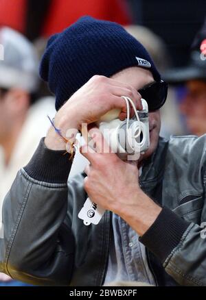 Zac Efron wearing beanie, holding camera at LA Lakers NBA game, December 2014 Stock Photo