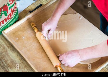 Close up of woman preparing home made fresh pasta the traditional way at home. Rolling pasta dough with rolling pin Stock Photo