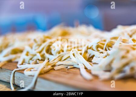 Close up of home made fresh pasta cut in slices on cutting board. Chopping pasta dough in the kitchen Stock Photo