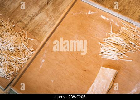 Step by step process of preparing home made fresh pasta the traditional way at home on cutting board. Chopping pasta dough in the kitchen Stock Photo