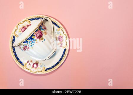 Empty coffee cup and saucer isolated on pastel pink background with copy space. Vintage tea cup with floral pattern made of fine bone china Stock Photo