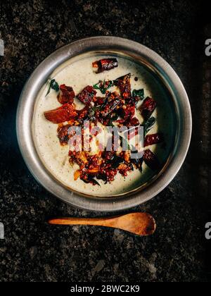 South indian spicy food chatni with red chillies in a vessel with a spoon beside it . Stock Photo