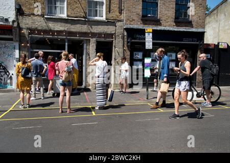 Hackney,London May 2020 during the Covid-19 (Coronavirus) pandemic. Broadway Market.. Queuing to buy fish at Fish and Flounder. Stock Photo