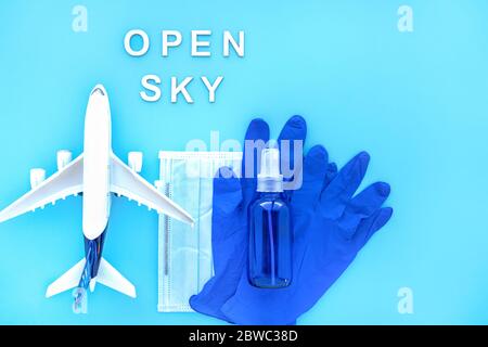 Travel after pandemic. Open sky after coronavirus. Plane, Blue passport with medical mask, Protective gloves, Bottle of Hand Sanitizer. Safe vacation Stock Photo