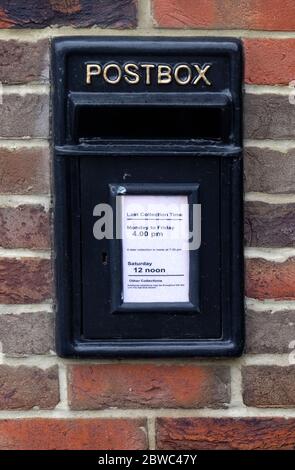 A normally red post box inserted into a brick wall has been painted black as it is no longer in service but is of local historical interest. Stock Photo