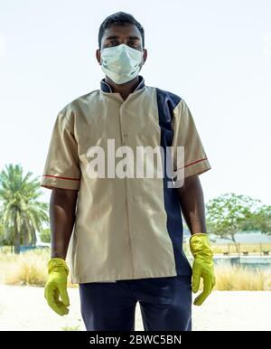 an indian garden man employee in sheikh zayed grand mosque, wearing hand gloves and face mask during work Stock Photo