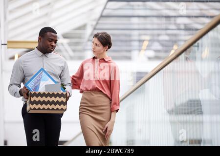 Waist up portrait of young female manager supporting African-American man leaving job, copy space Stock Photo