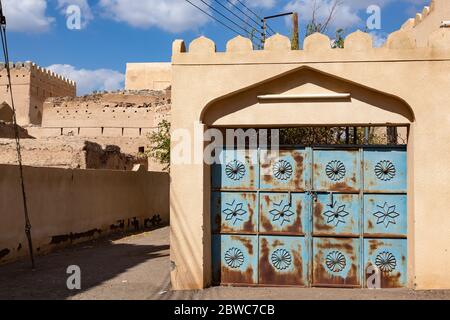 Rusty blue gate with embellishment in a wall in old town of Al Mudairib in Oman Stock Photo