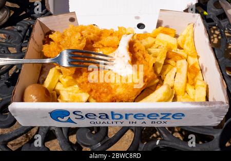 Takeaway,  Fish and Chips served in a Seabreeze brand cardboard box, on an outdoor metal table top Stock Photo