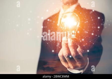 Business man holding a light bulb with sky and copy space for accounting, ideas and creative concept. Stock Photo