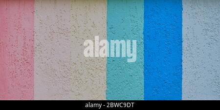 Texture of a wall covered with seven multicolored vertical stripes of textured stucco as a background. Banner Stock Photo