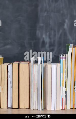 School readings. Stack of many books. A school board in the background is not thoroughly wiped with a sponge. Traces of chalk on the chalkboard. Stock Photo