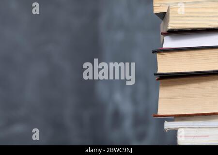 School readings. Stack of many books. A school board in the background is not thoroughly wiped with a sponge. Traces of chalk on the chalkboard. Stock Photo