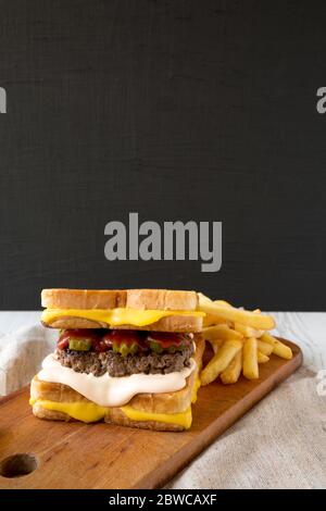 Homemade Grilled Cheese Burger with French Fries on a rustic wooden board, side view. Copy space. Stock Photo