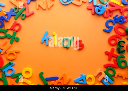 Kids words in colorful plastic letters on orange background. Stock Photo