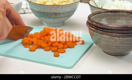 Chef chopping carrot, cooking vegetables or soup. Close up view, white background Stock Photo