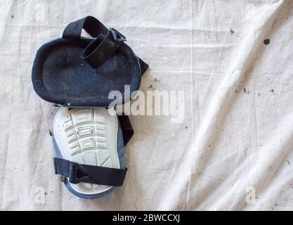 a well worn pair of painter's kneepads lying on a paint spotted drop cloth with copy space Stock Photo
