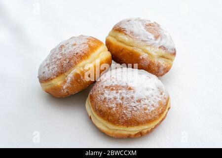 three donuts sprinkled with icing sugar on a light surface Stock Photo