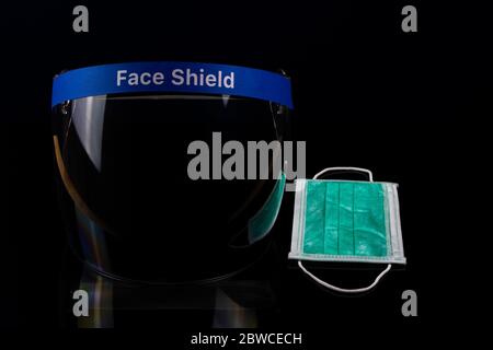 Face shield and a surgical mask to protect against viruses on a dark background. Stock Photo