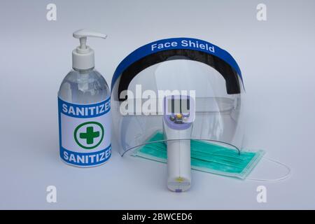 Face shield, infrared thermometer, surgical mask, and hand sanitizer gel. Coronavirus prevention concept. Stock Photo