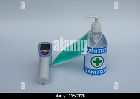 Infrared thermometer, surgical mask, and hand sanitizer gel. Concept of Coronavirus pandemic protection. Stock Photo
