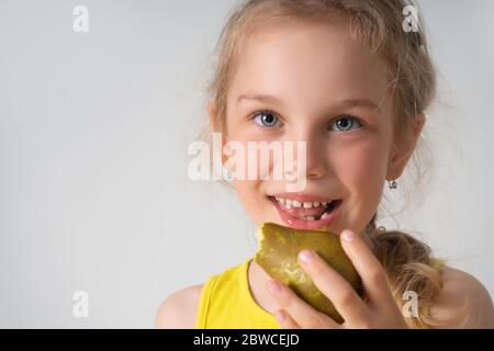 Happy little girl preschooler eating ripe juicy pear with great pleasure. Close up studio portrait isolated on white, copy space Stock Photo