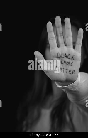 Portrait of white girl holding hand with slogan Black Lives Matter. Peaceful protest in solidarity with BLM movement. Stock Photo