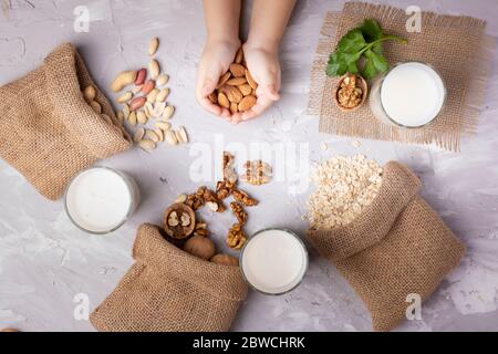 Mix of Nuts in sackclothes, eco bags near nut milk, holing cashew. Flat lay Stock Photo