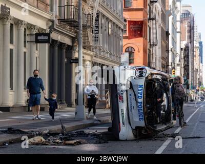 New York, New York, USA. 31st May, 2020. People walk by a NYPD vehicle burned in SoHo during the previous night's violent protests over George Floyd's death. Credit: Corine Sciboz/ZUMA Wire/Alamy Live News Stock Photo