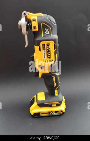 OTTERY ST MARY, DEVON - FEBRUARY 6TH 2020: Dewalt Cordless Multi Tool stands upright on its battery on a black background. Stock Photo