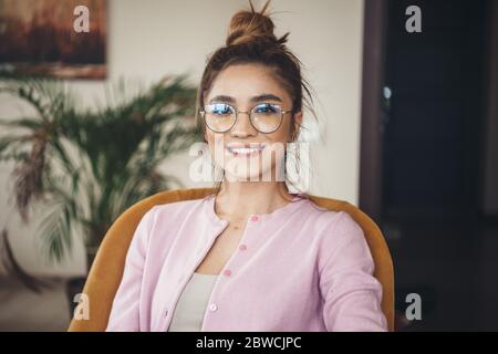 Lovely caucasian woman with eyeglasses smiling at camera toothy while wearing a pink jacket Stock Photo